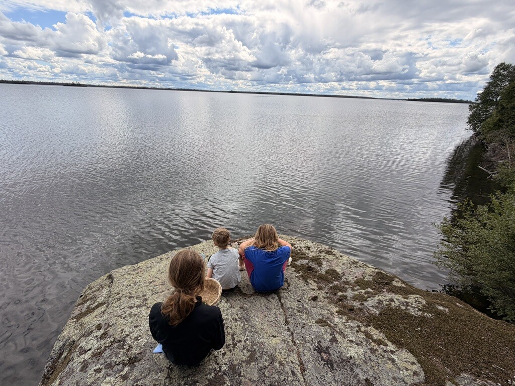 Children sitting together at the rocky edge of Besnard Lake