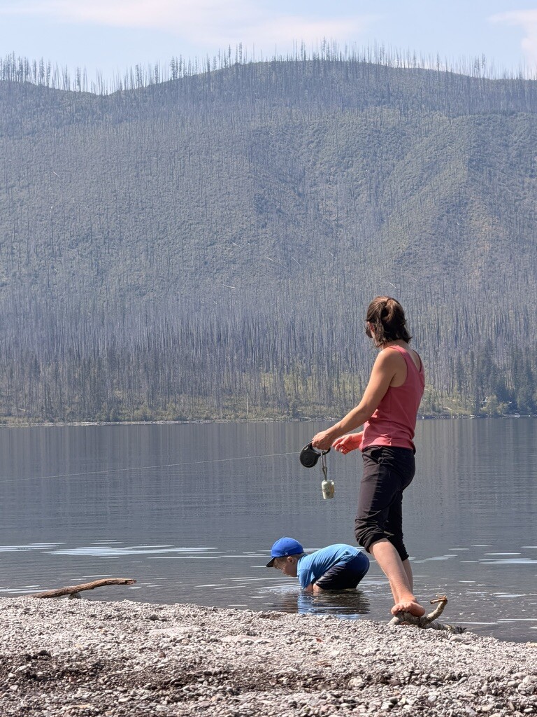 Birch wading in Lake McDonald while Stacey stands at the water's edge