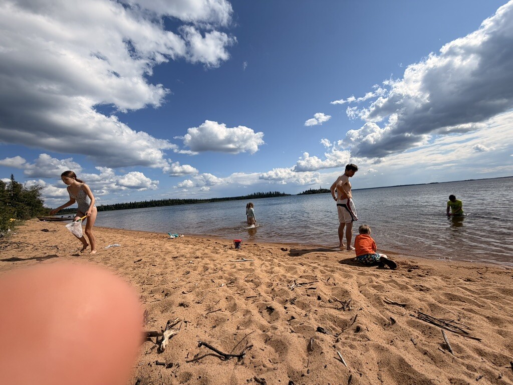Children playing in the water beneath a wide blue sky at Long Beach