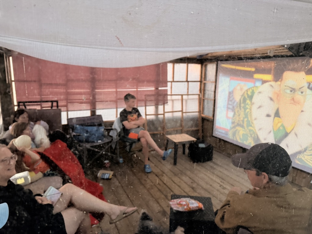 Minions projected on a screen while the family watches in the gazebo