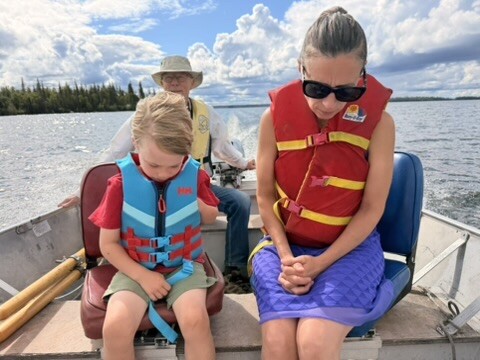 Children in life jackets on the boat beneath a cloudy sky