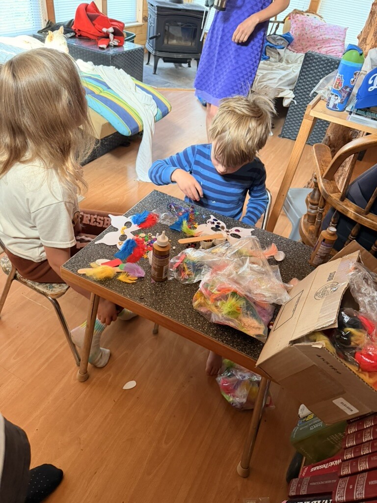 Children making Sarah's birthday card at the cabin table