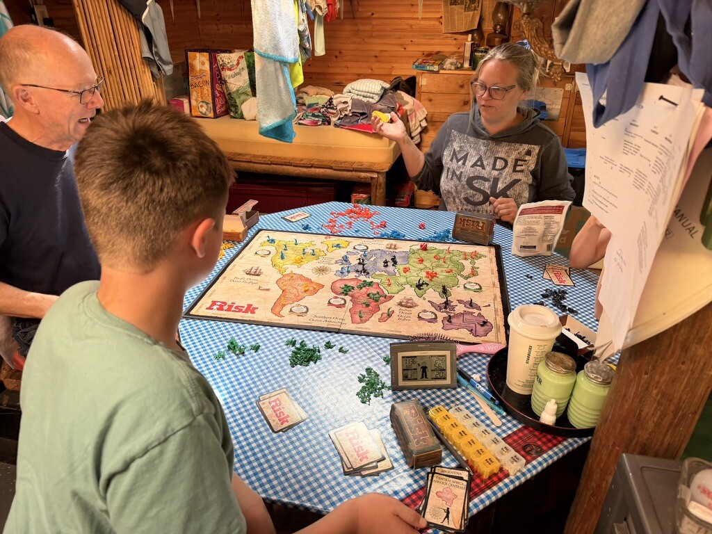 Family continuing their Risk game around the cabin table on Tuesday