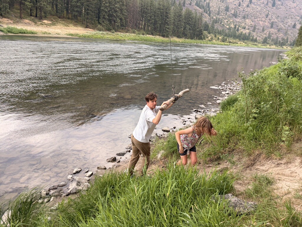 A child climbing the riverbank after swinging over the water