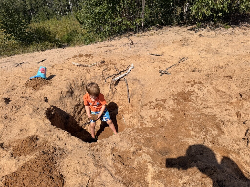 Children inside the enormous hole dug in the sand