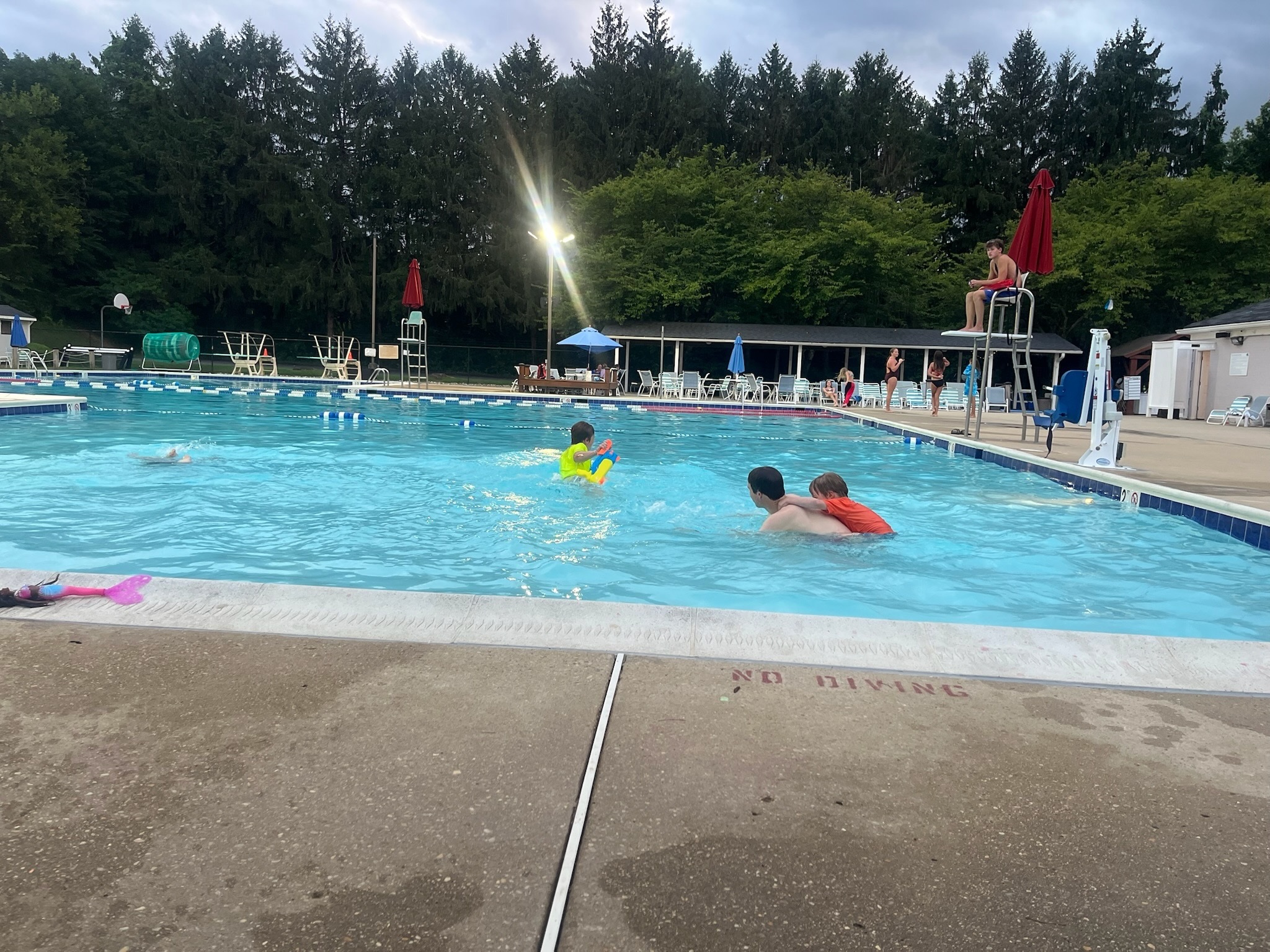The children swimming in the neighborhood pool on the first evening
