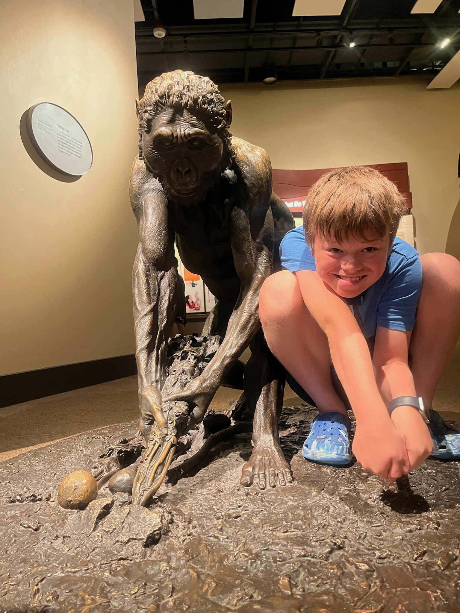 Birch crouching beside an early human figure in the Hall of Human Origins