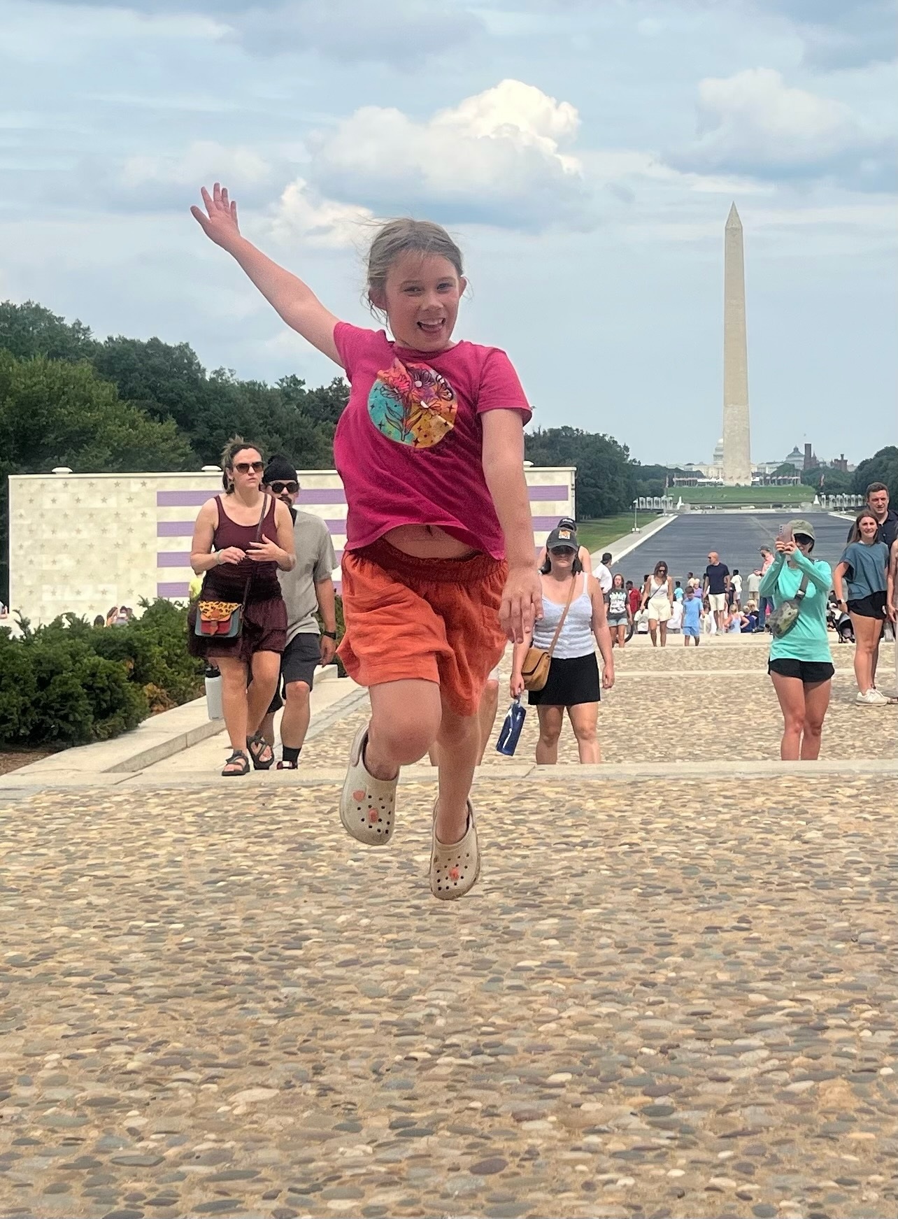 Maple jumping on the National Mall with the Washington Monument behind her