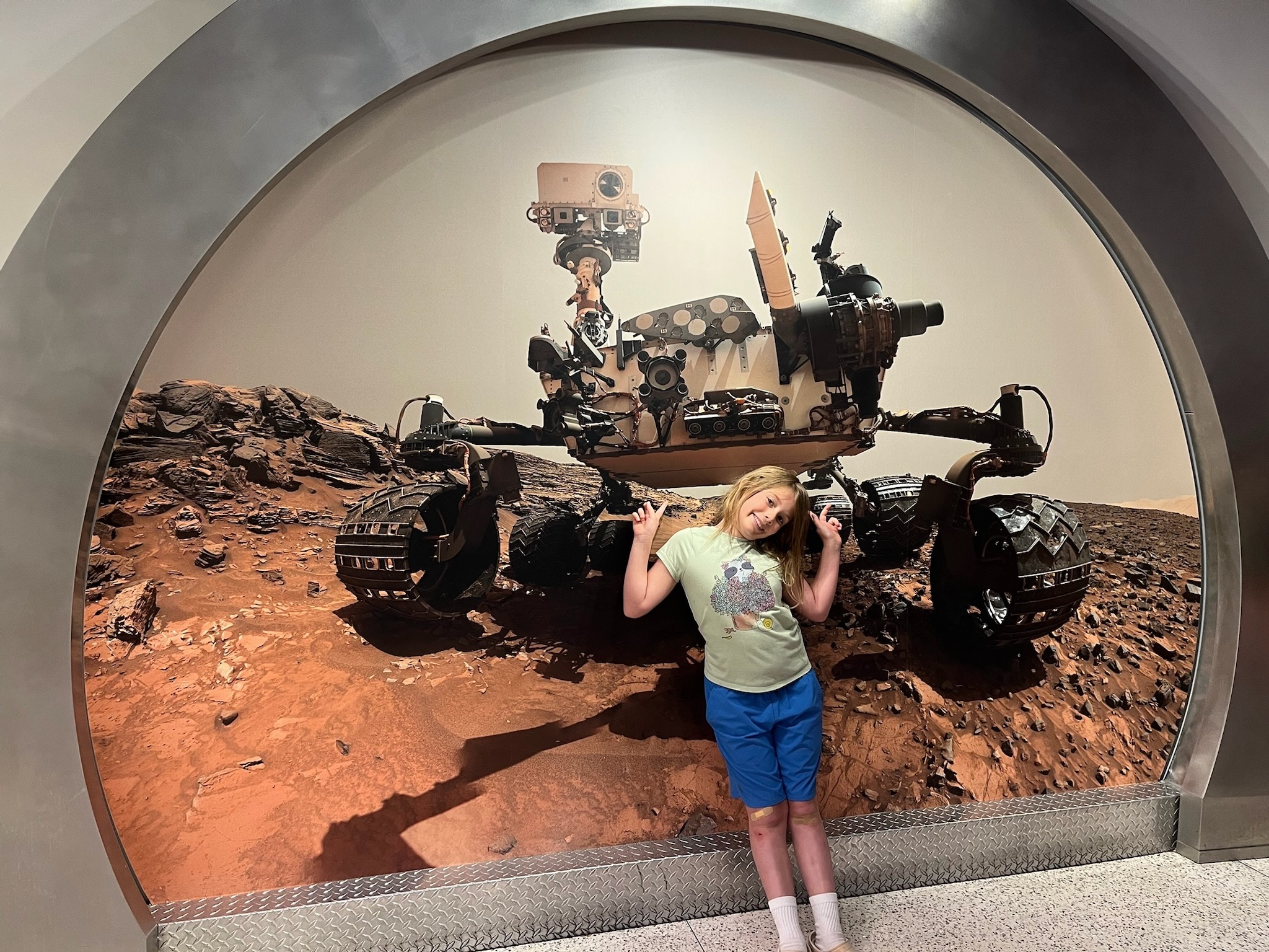 Maple posing in front of a Mars rover display