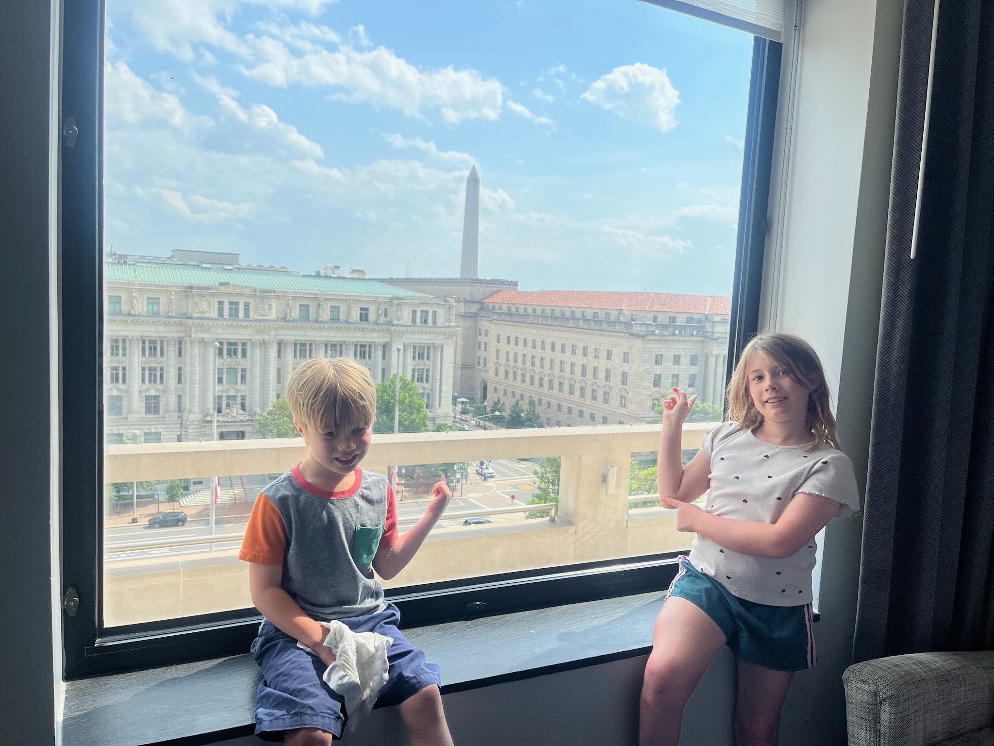 The children sitting in the hotel window with the Washington Monument in view