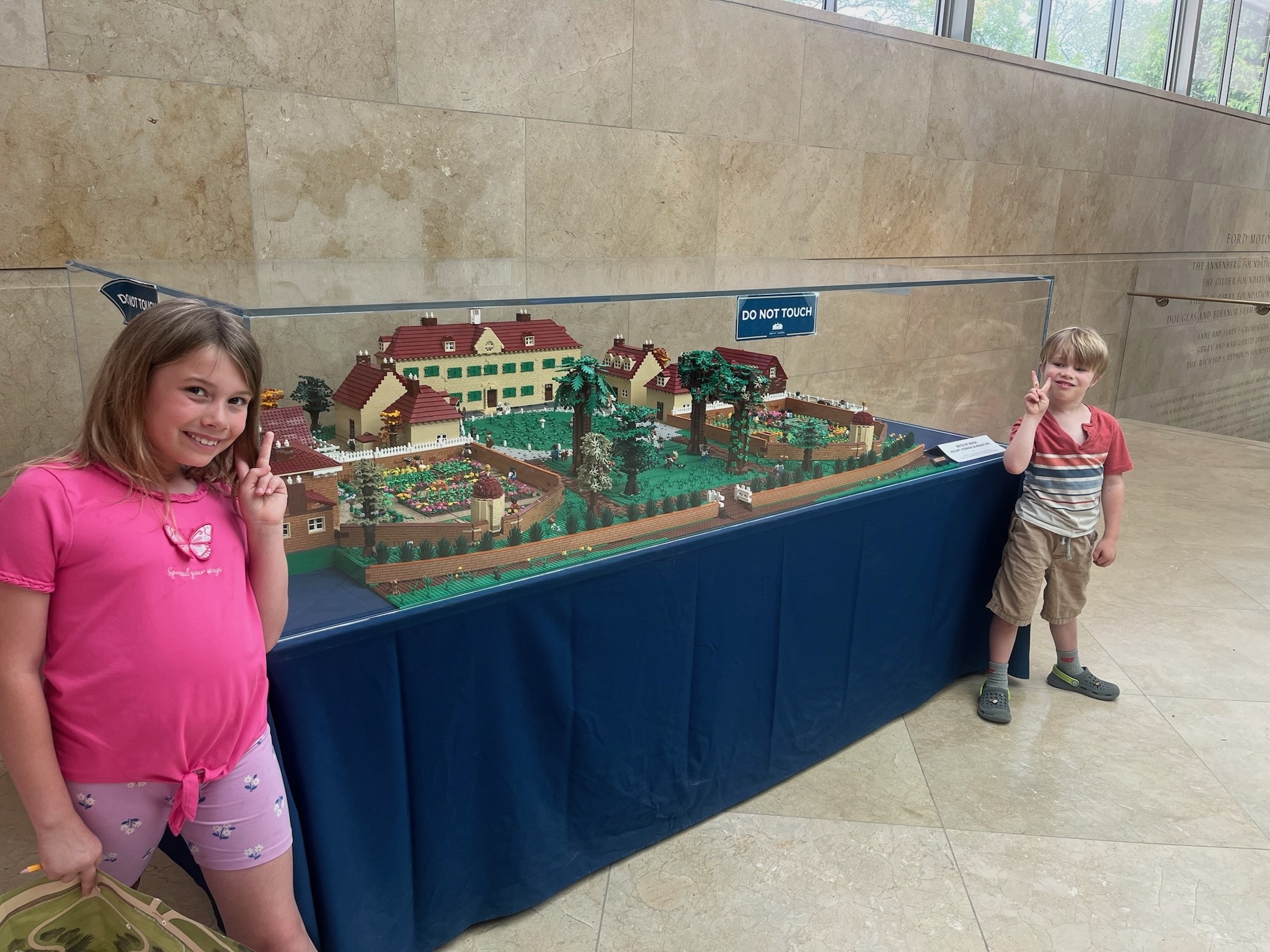 Three children posing beside a model of Mount Vernon