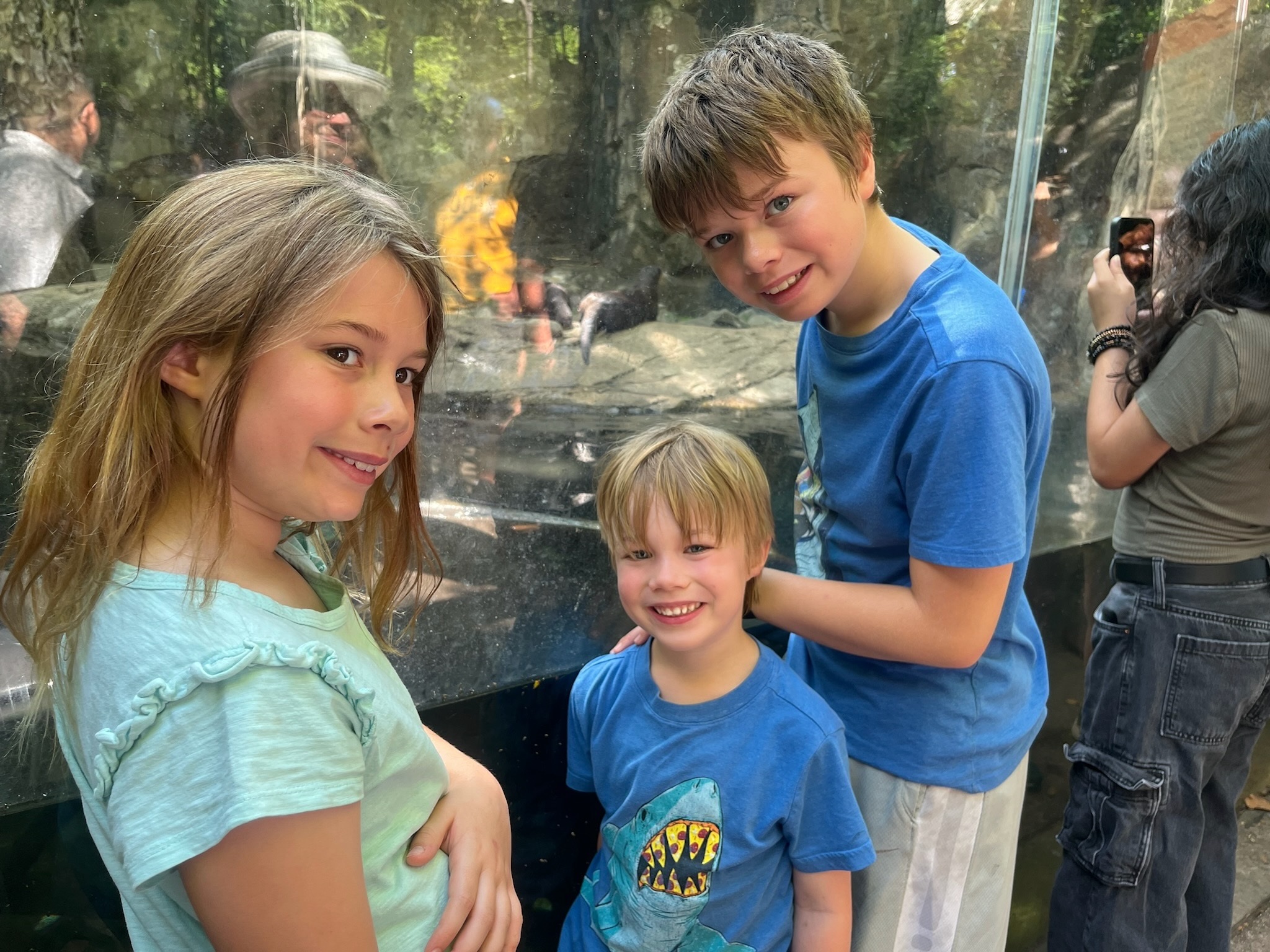 Three children smiling beside an animal habitat at the National Zoo